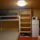Pravá část chatky, pohled na spací pódium, palandu a lednici v kuchyňce